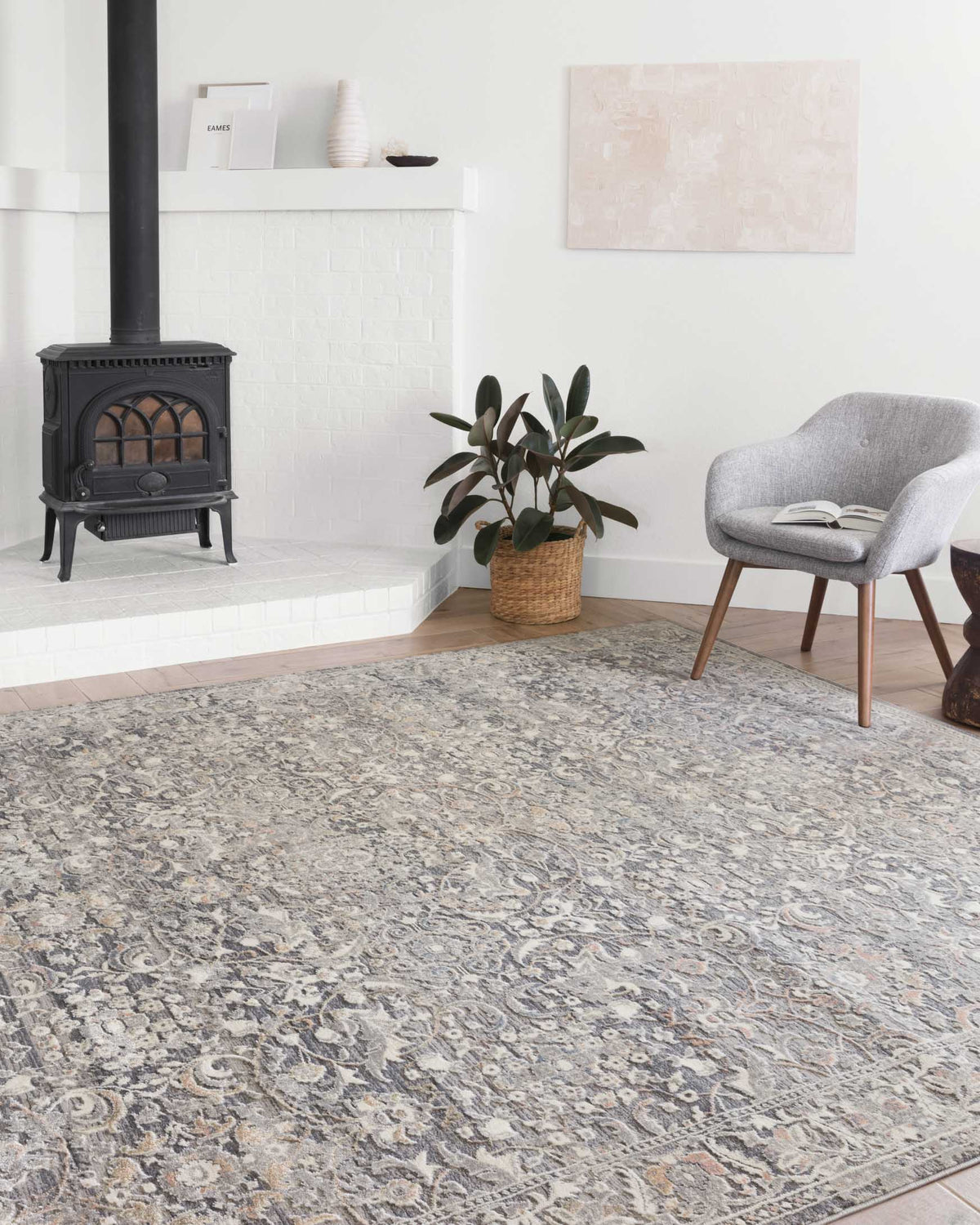 Grey and mist ornate area rug laid across the floor with detailed scrolling motifs.