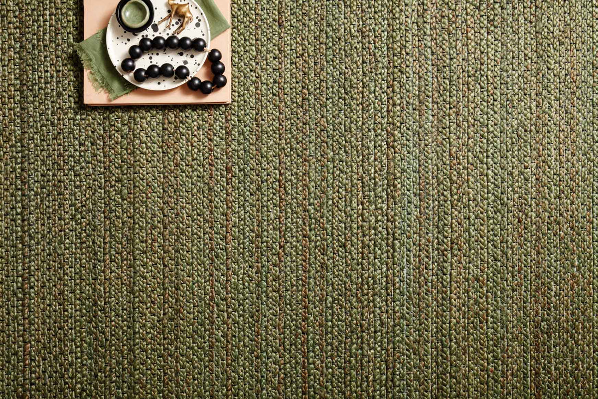 Green textured hand-woven rug with multicolor flecked fibers and tight looped pattern.