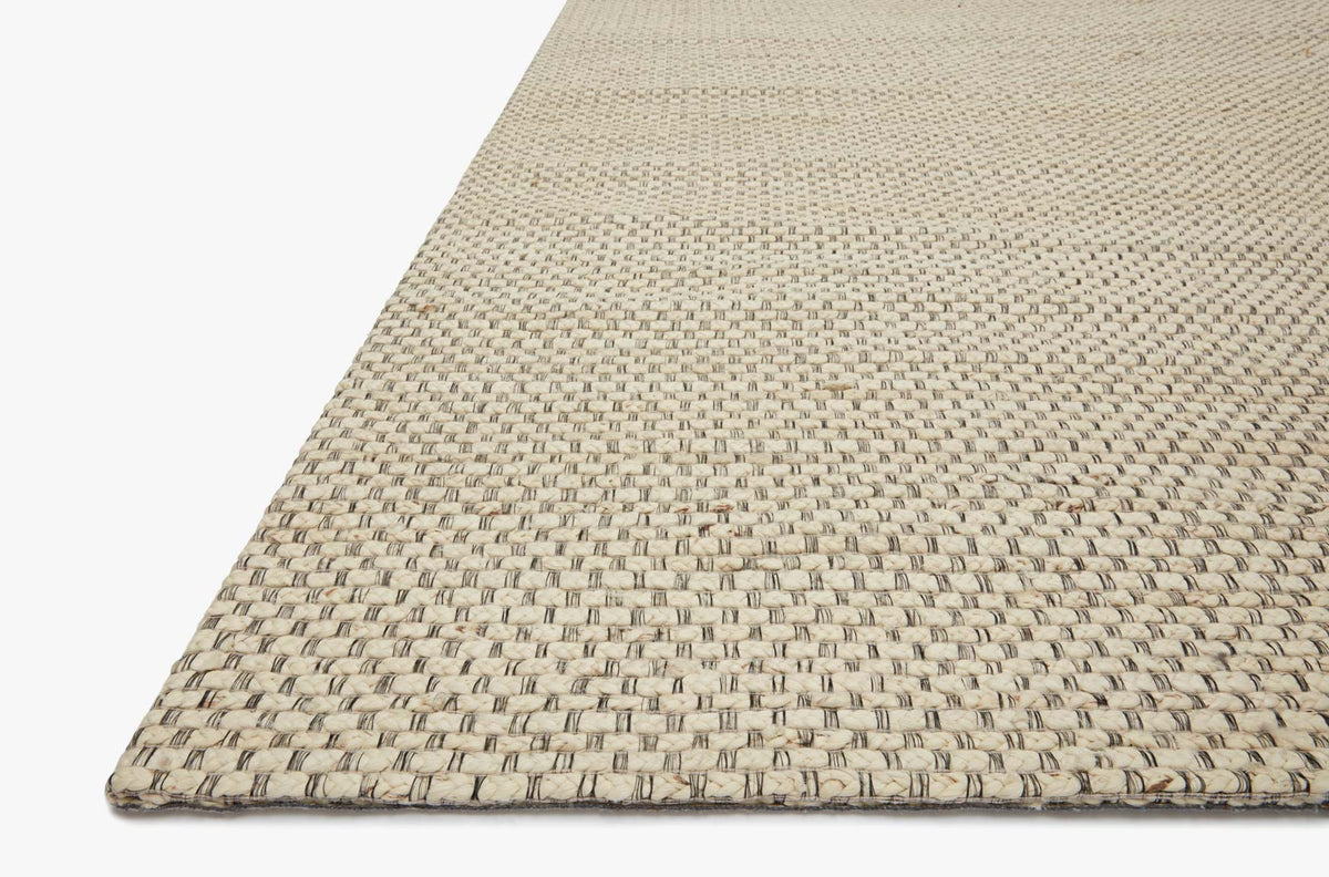 Hand-woven ivory rug corner with textured flat braided weave and border trim.