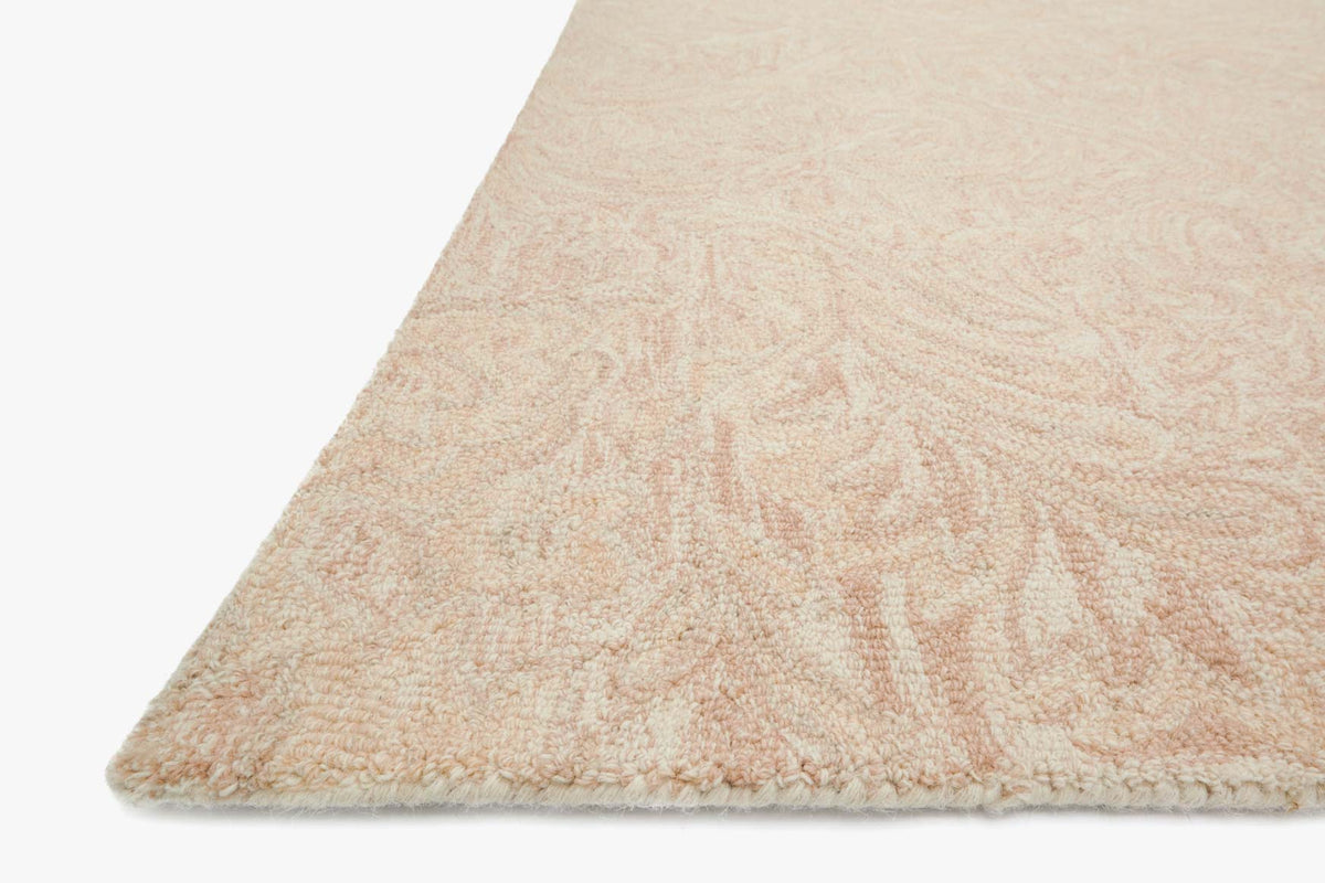 Blush hooked rug with textured surface and swirling leaf pattern corner