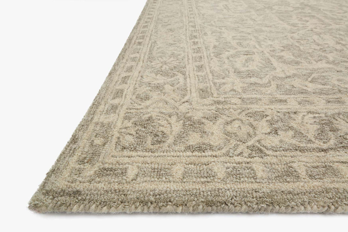 Light stone beige hooked rug corner with detailed pattern and short fringe edge