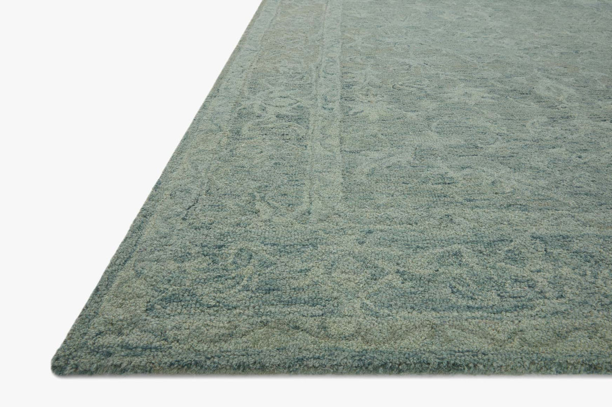 Teal hooked rug corner with textured cut-pile and subtle floral pattern