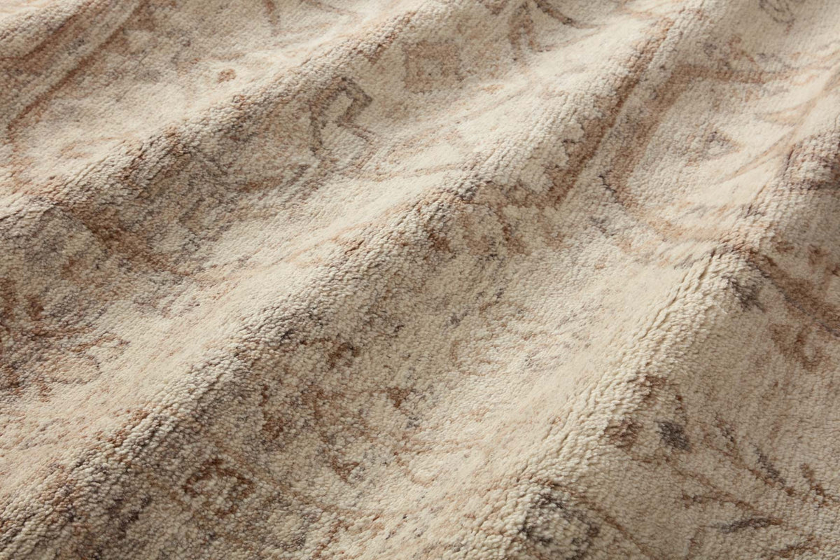 Close-up of natural woven rug with abstract motifs in light brown and taupe.