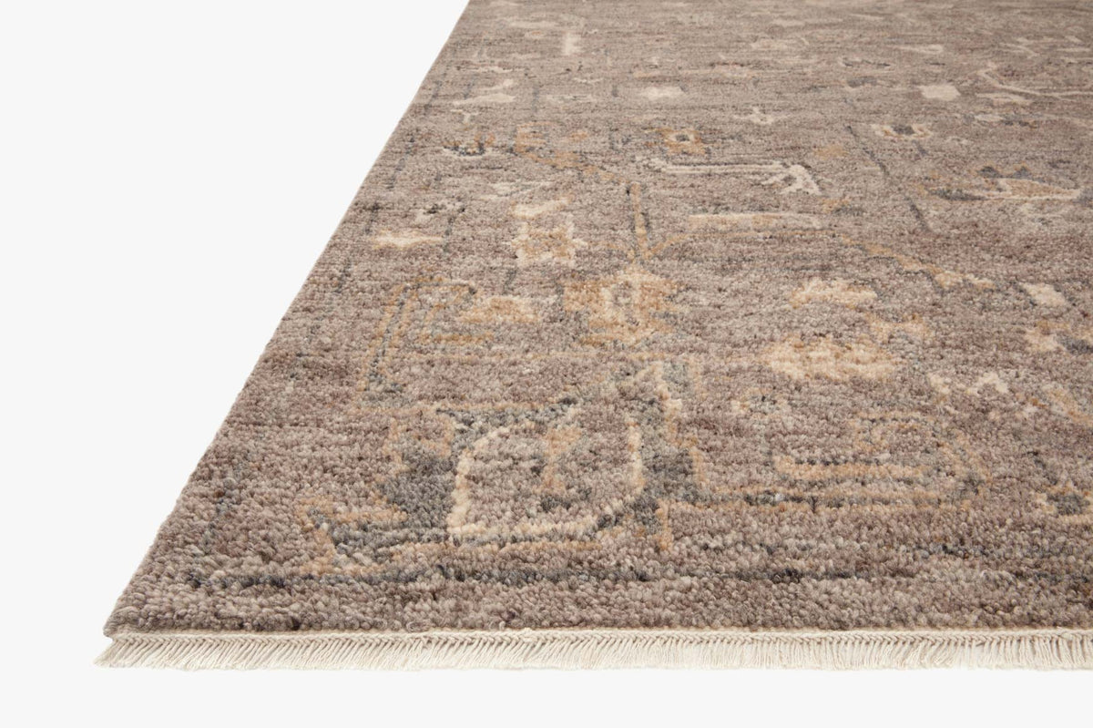 Corner view of traditional hooked rug with geometric pattern and light fringe edge