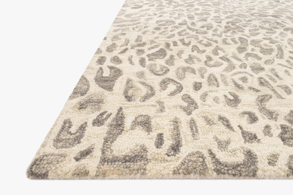 Corner view of grey and ivory hooked rug with abstract pattern texture and short pile.