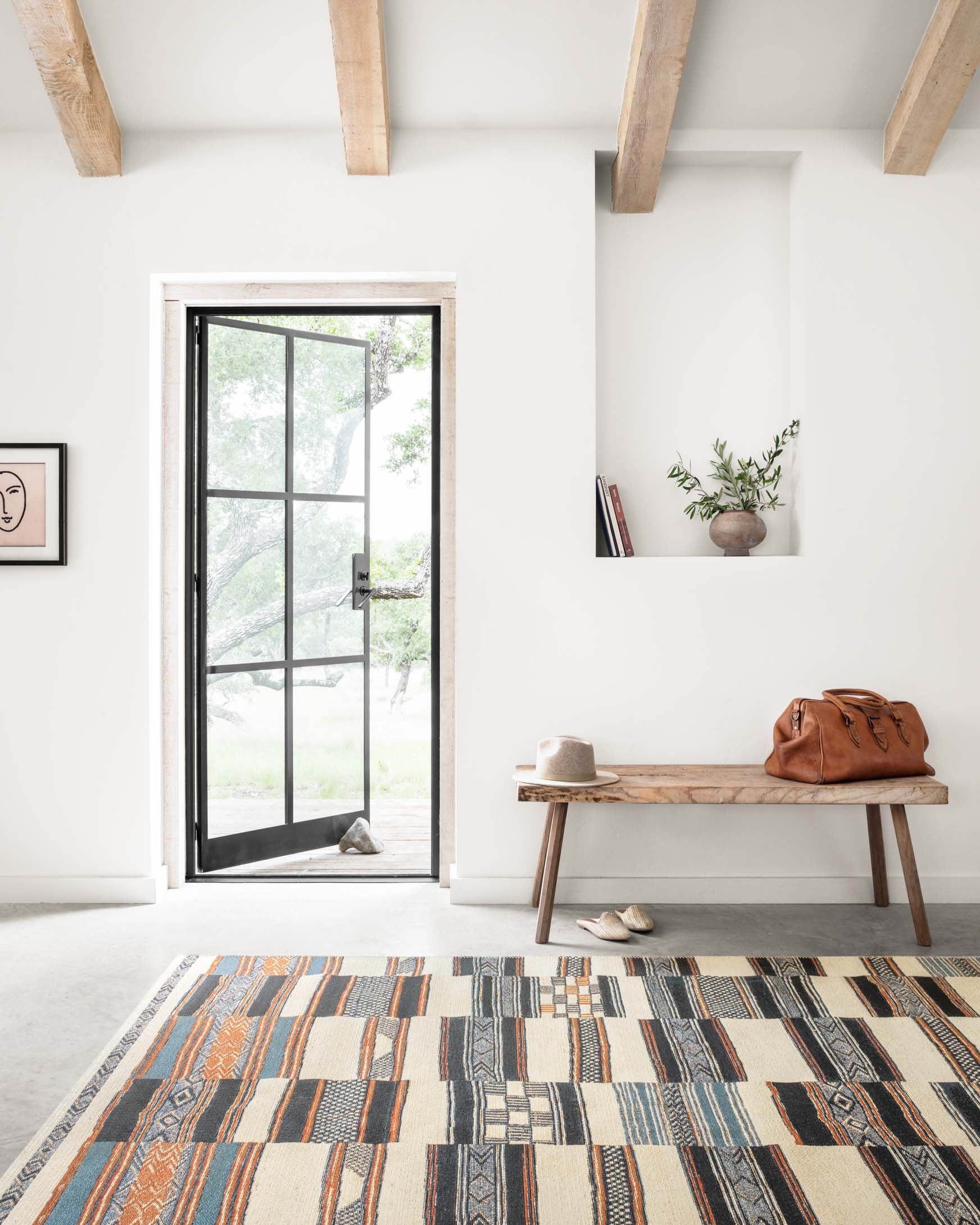 Geometric patchwork area rug in ivory with blue, navy, and orange stripes