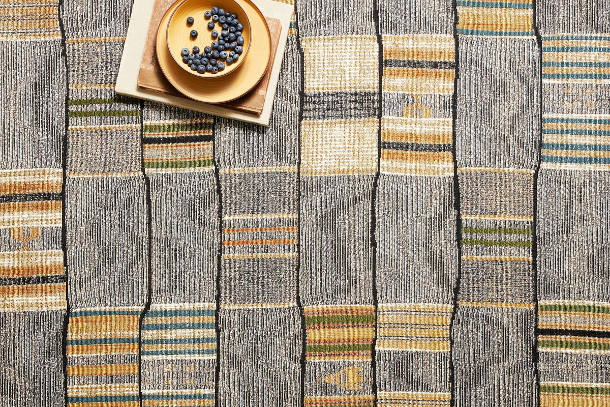 Close-up of gray-and-gold woven rug pattern with thin blue and orange stripe lines