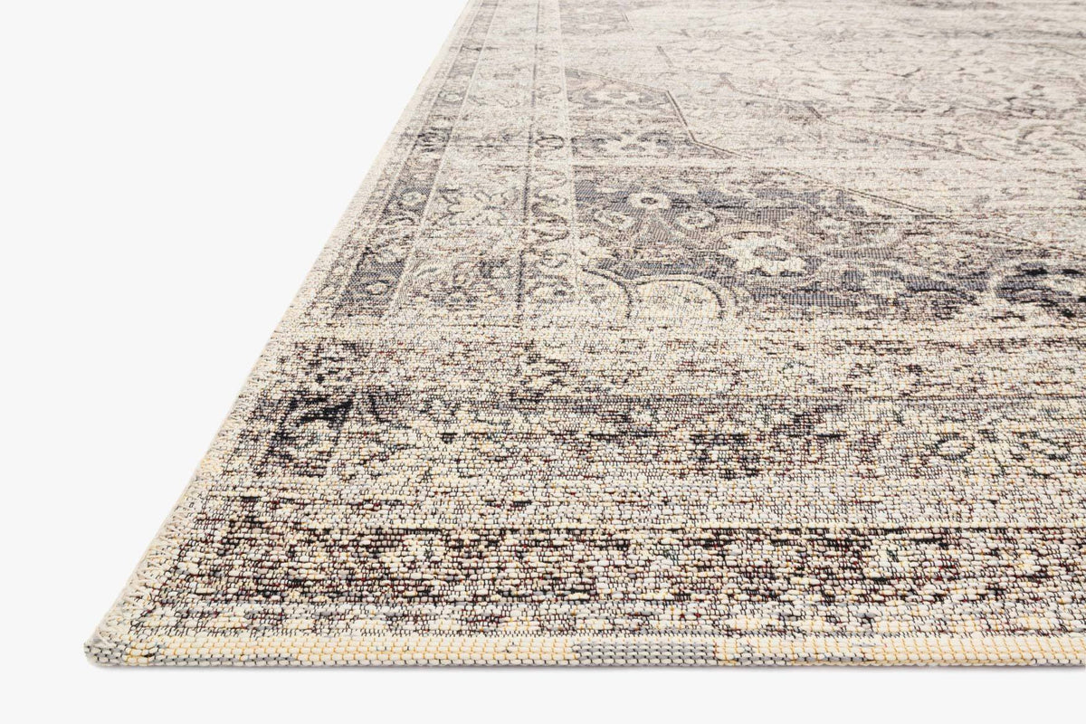 Stone-and-ivory rug corner with patterned edge and flat woven texture.