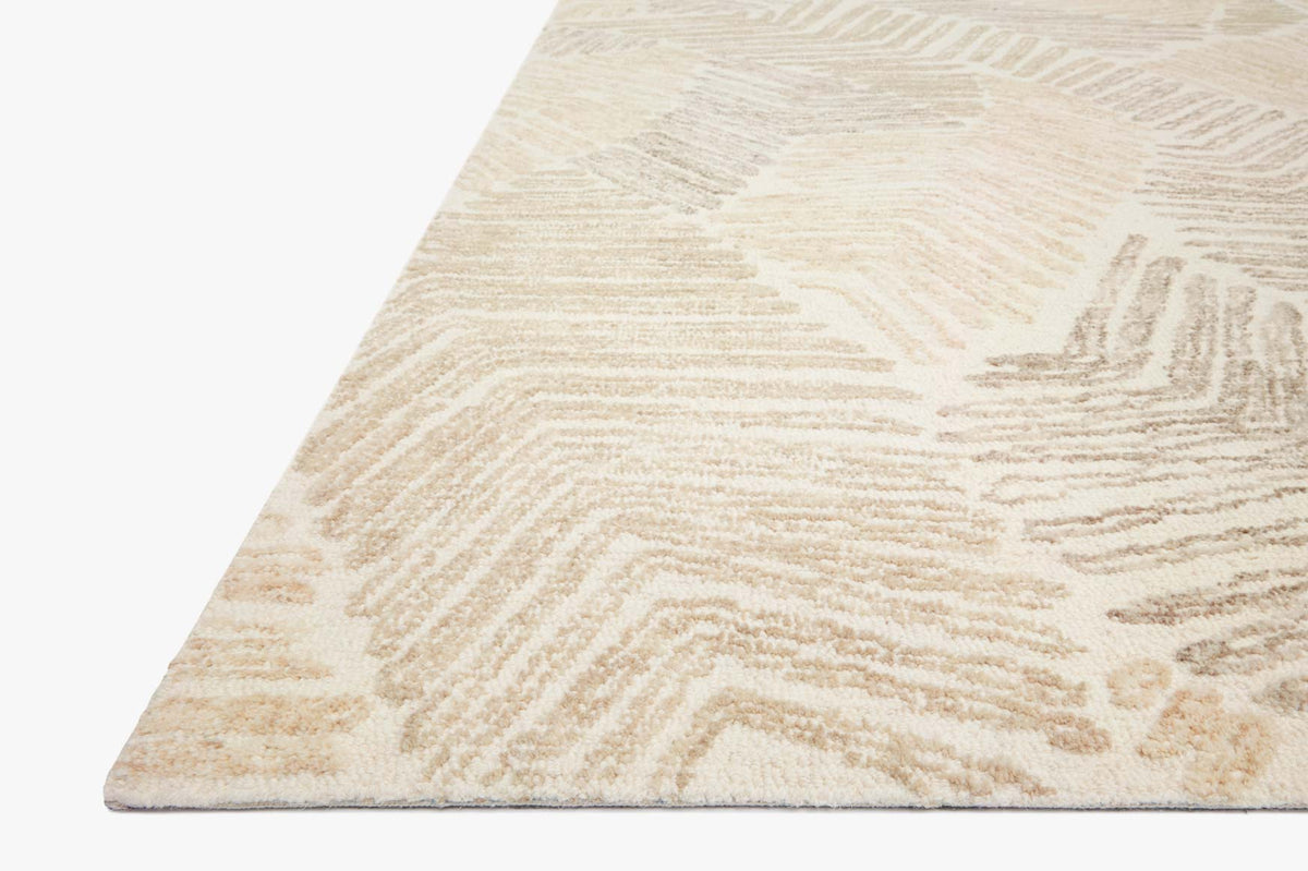 Corner of hand tufted area rug showing light base and raised tan geometric pattern