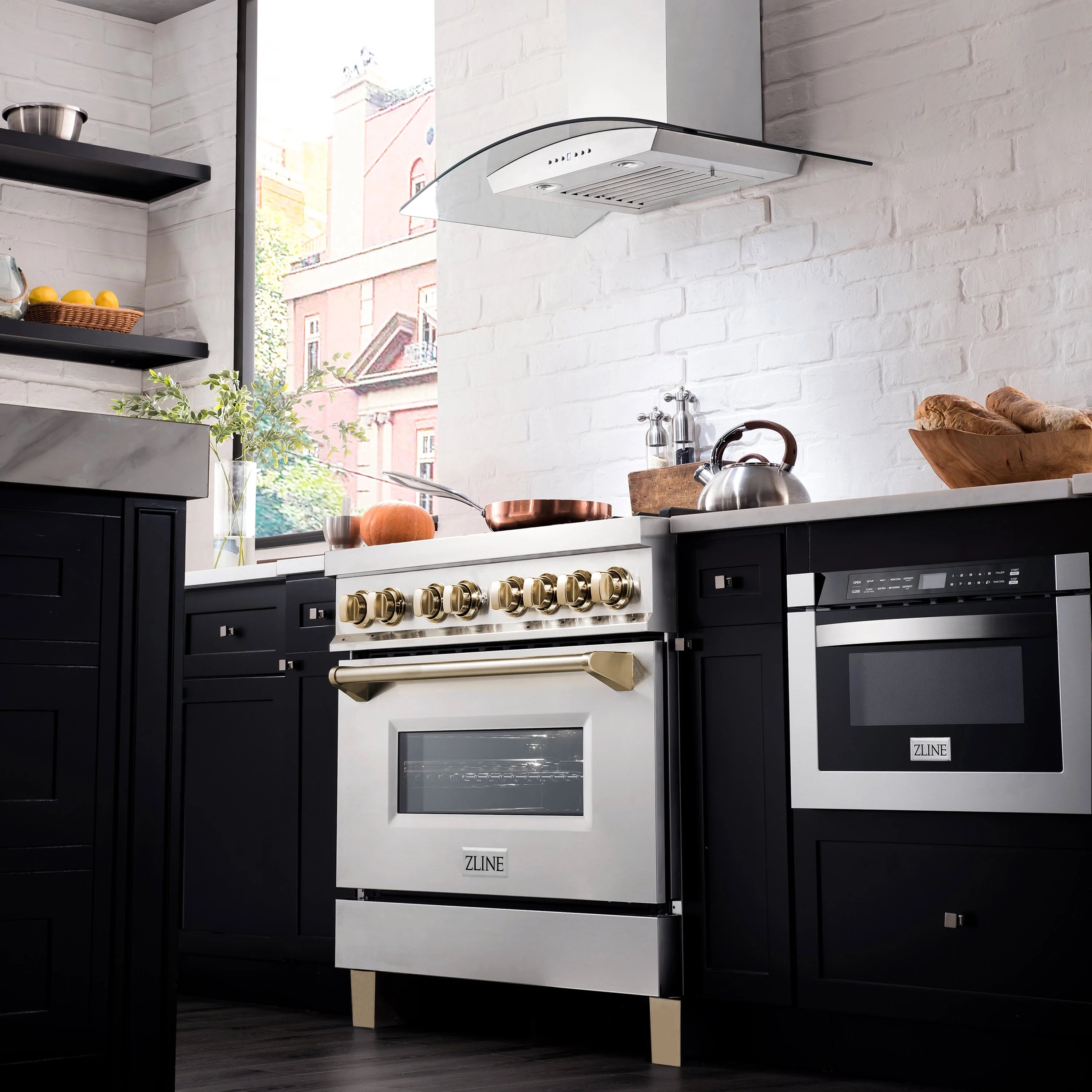 Stainless steel dual fuel range with gold knobs and wall hood, three-quarter view