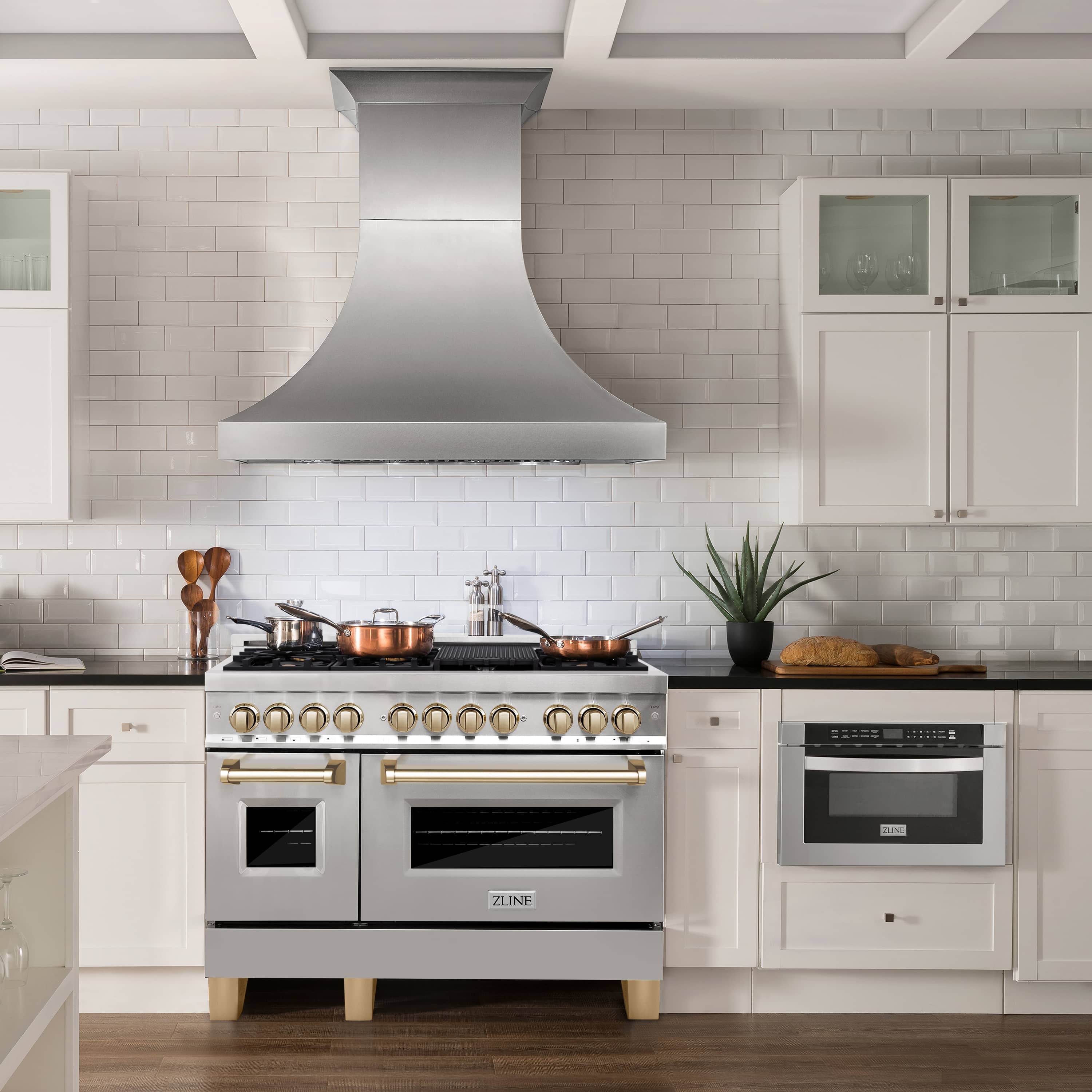 Stainless dual fuel range with gold knobs, gas burners, and black oven doors