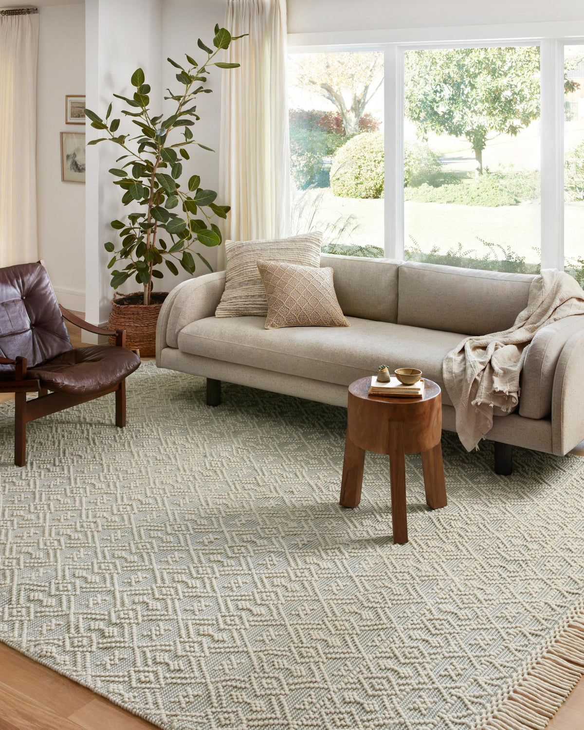 Ivory and light blue geometric rug with textured weave and fringe border under furniture