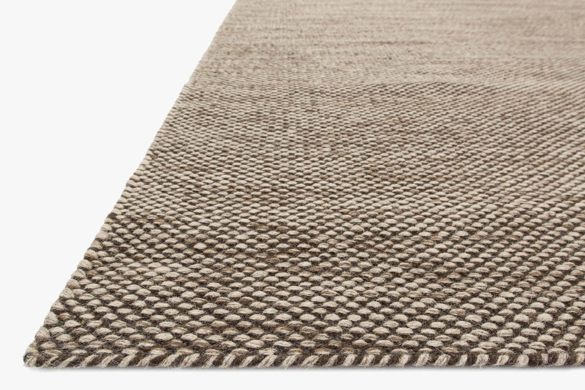 Stone hand-woven rug corner with raised texture and woven border detail