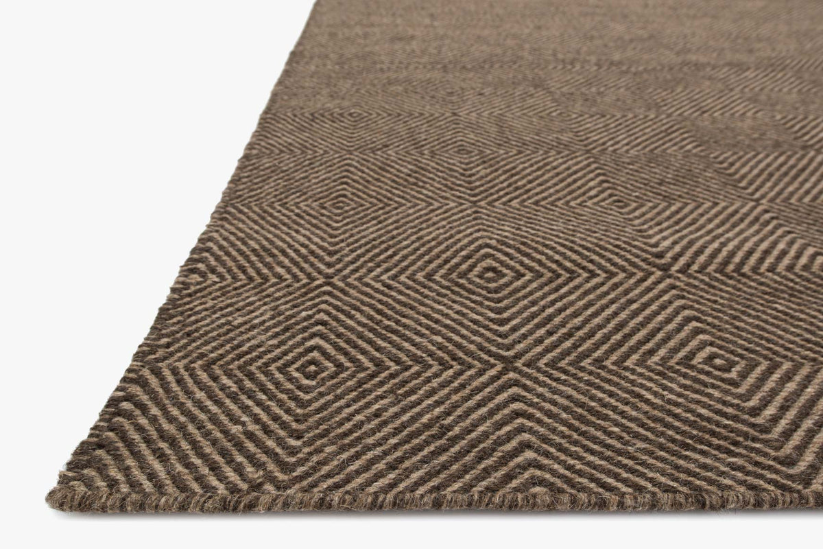 Transitional hand-woven rug corner with low-pile herringbone and diamond motifs