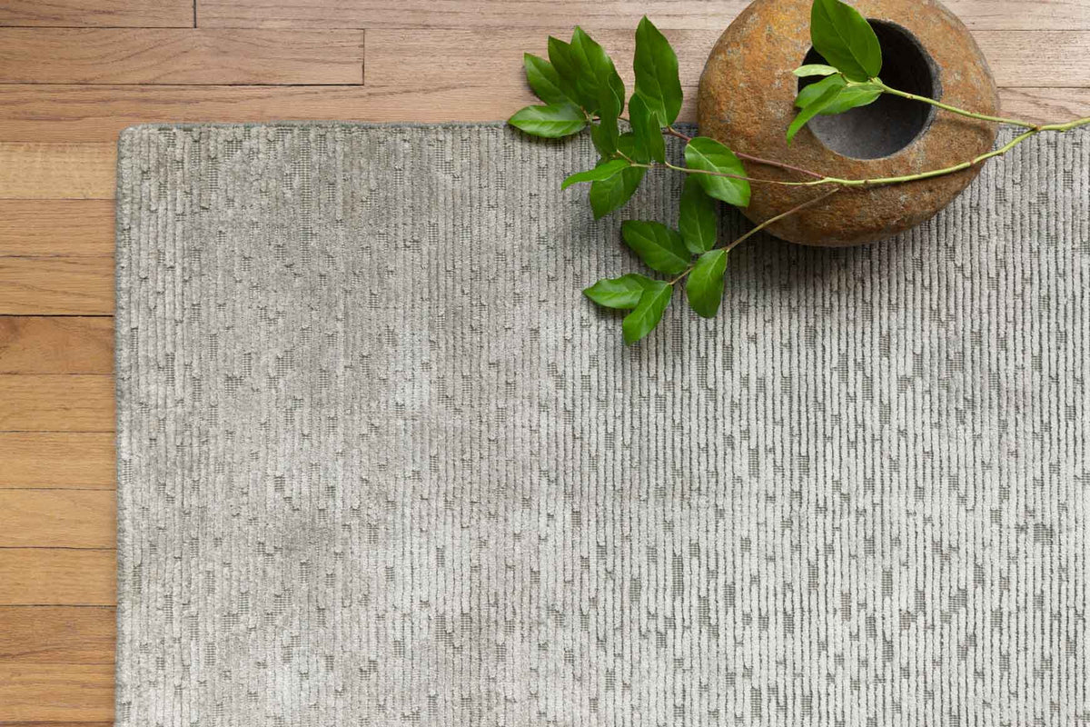 Grey hand-loomed rug with speckled texture, corner view.