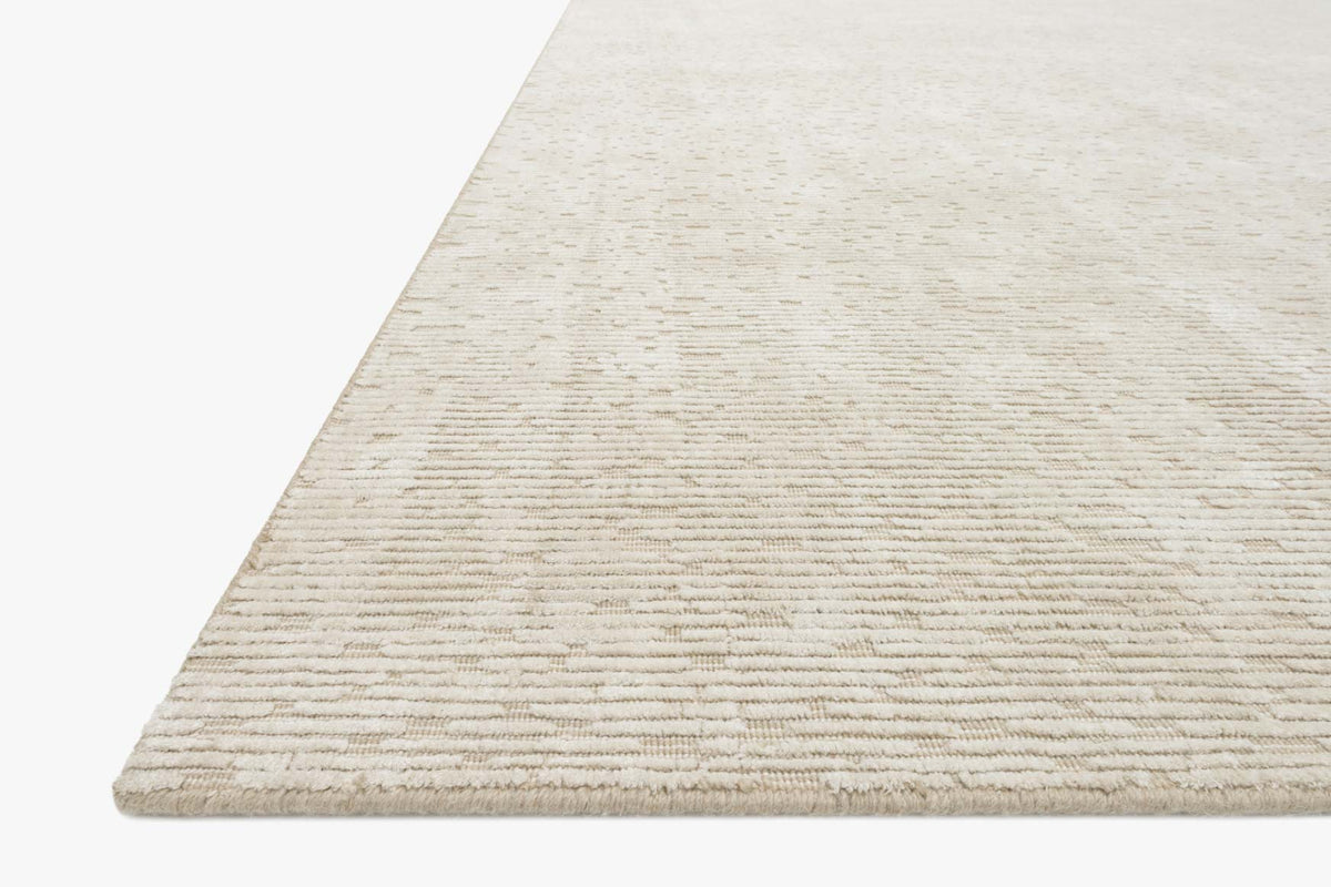 Ivory hand-loomed rug with textured surface and finished edge, corner view