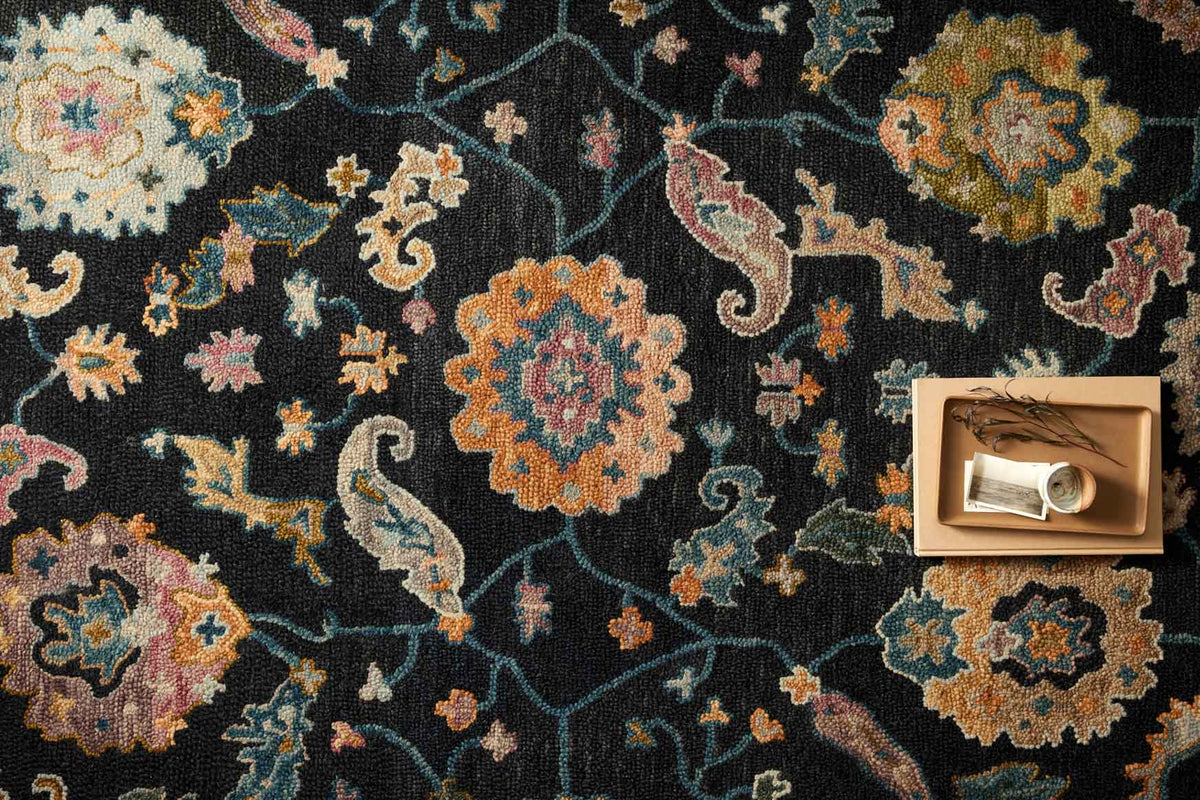 Black hooked rug surface with multicolor floral motifs and curved vine lines