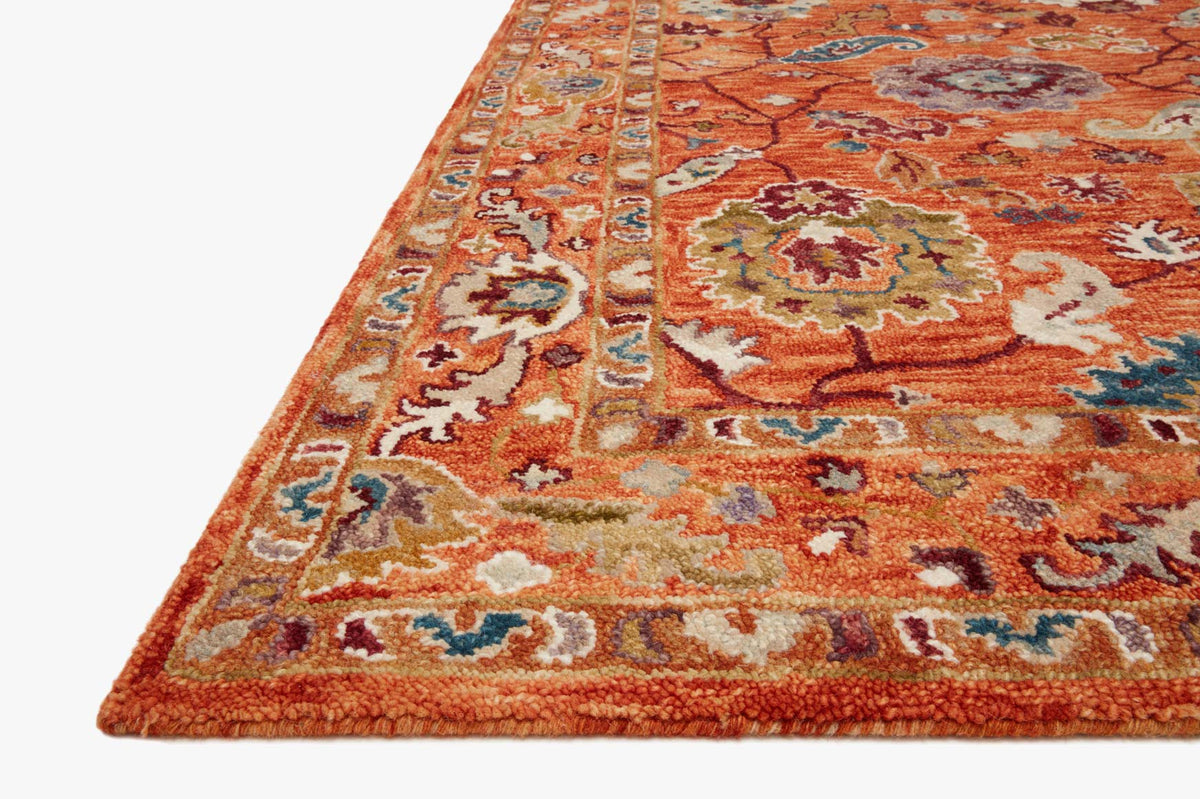 Orange rug corner detail with multicolor floral motifs and low-pile hooked texture