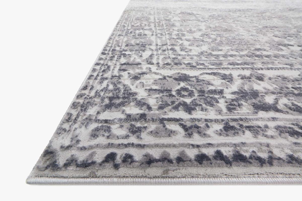 Light gray power-loomed rug corner with navy-blue ornamental border and medallions