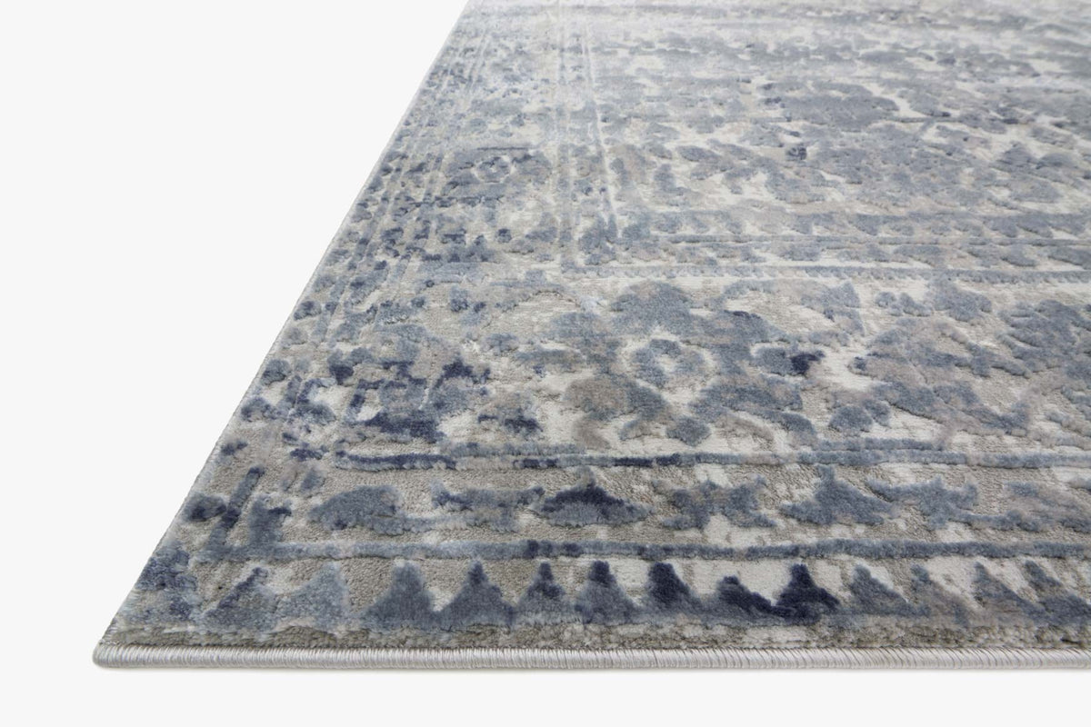 Blue and stone area rug corner view with textured damask pattern and flat edge