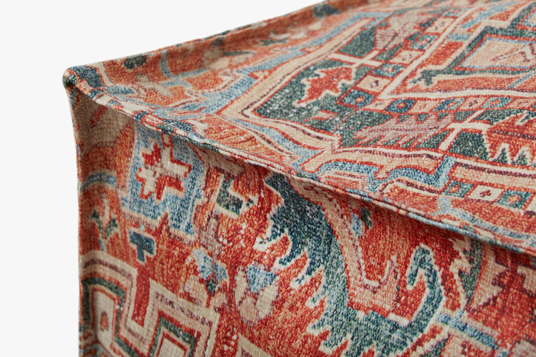Woven pouf corner detail with rust, teal, and cream geometric motifs