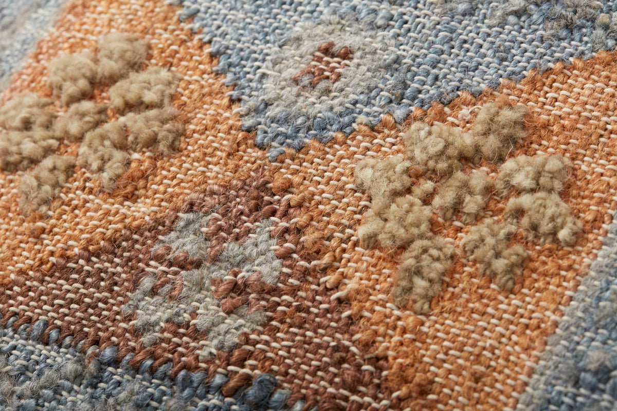 Hand-woven pouf fabric close-up with orange, beige, and blue raised tuft pattern