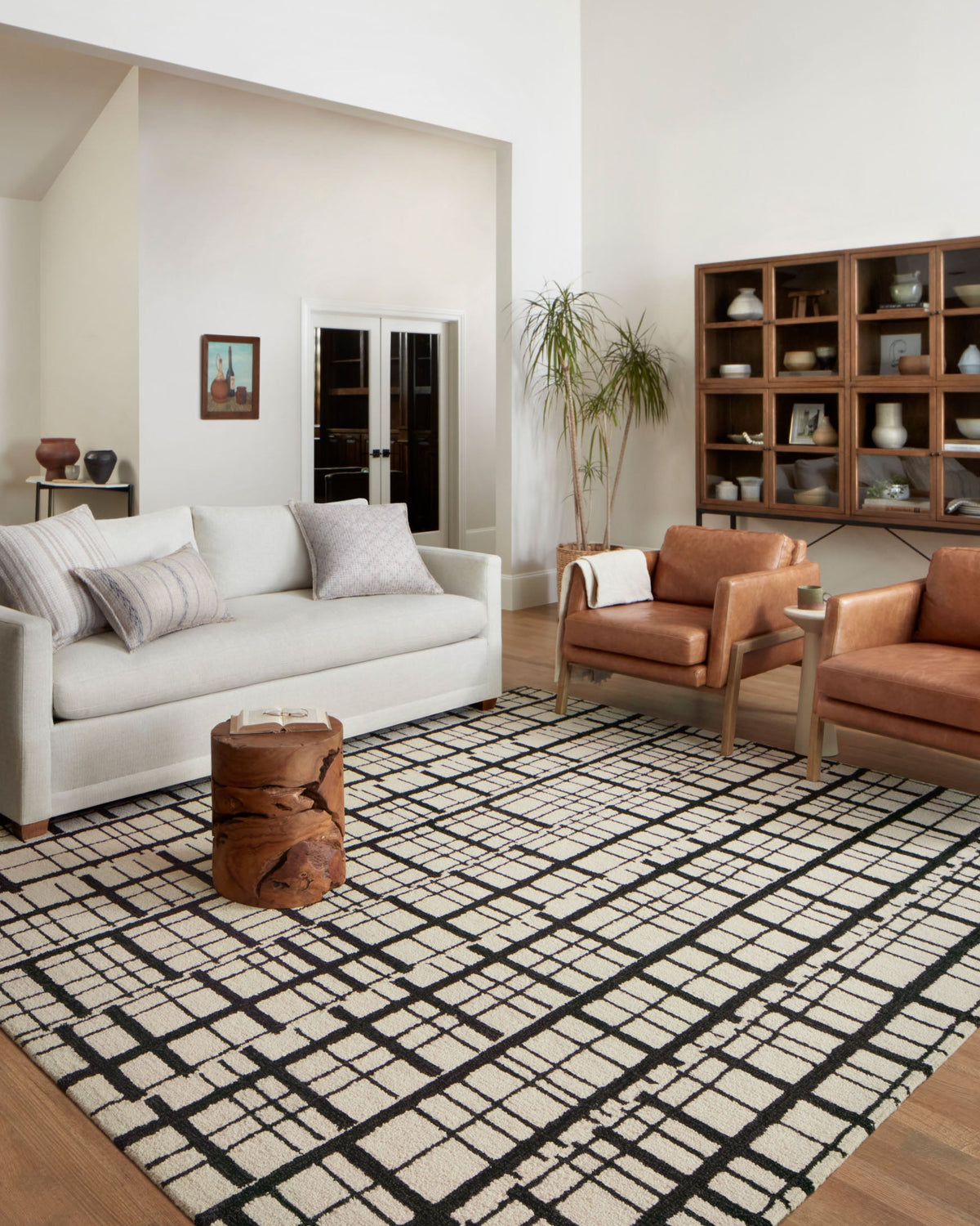 Black and ivory plaid grid hand-tufted rug on wood floor in a living room.