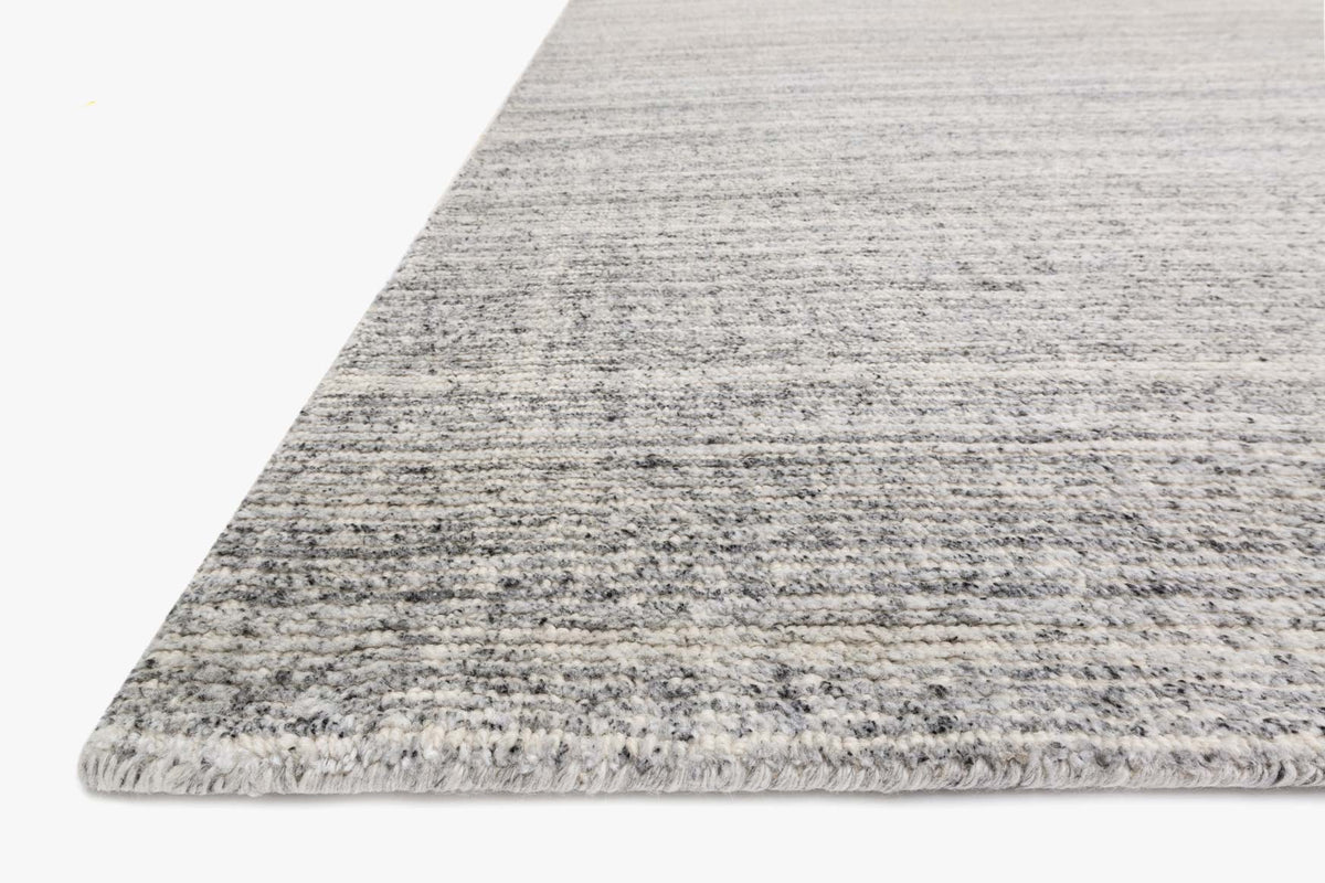 Charcoal gray hand-loomed rug corner with textured stripes and short fringe edge