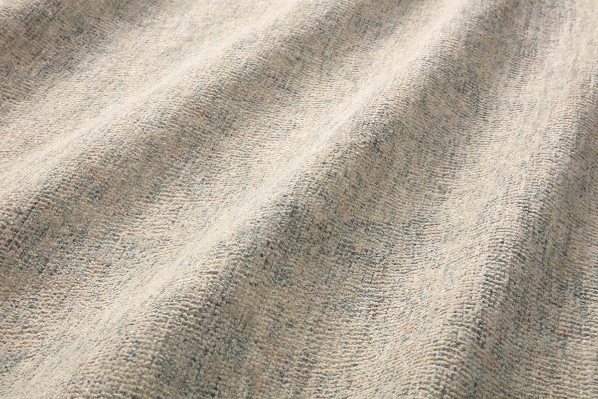 Hand-woven rug texture close-up in ivory with speckled blue-gray threads