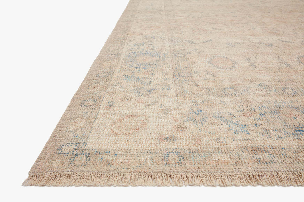 Transitional rug corner with fringe and light natural tones, subtle blue motif.
