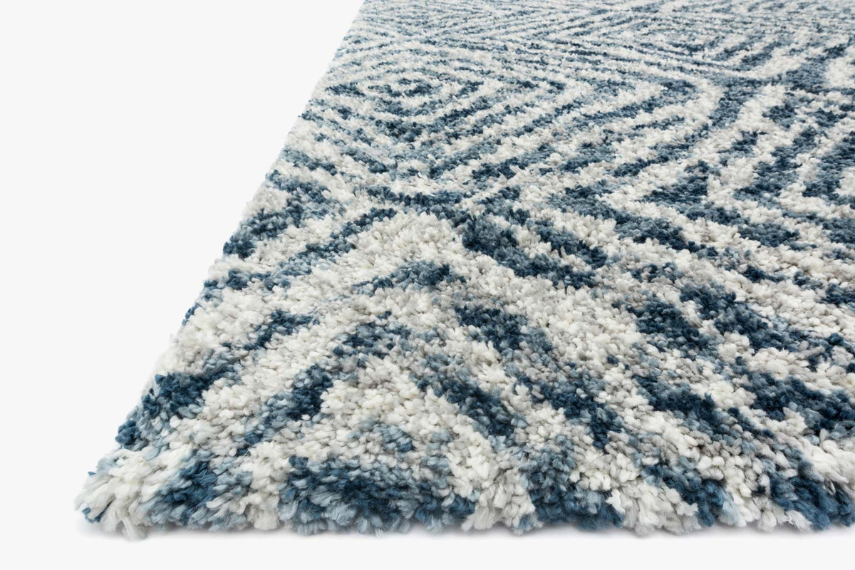 Shag rug corner with fringed edge, blue and cream geometric pattern in ocean and pebble