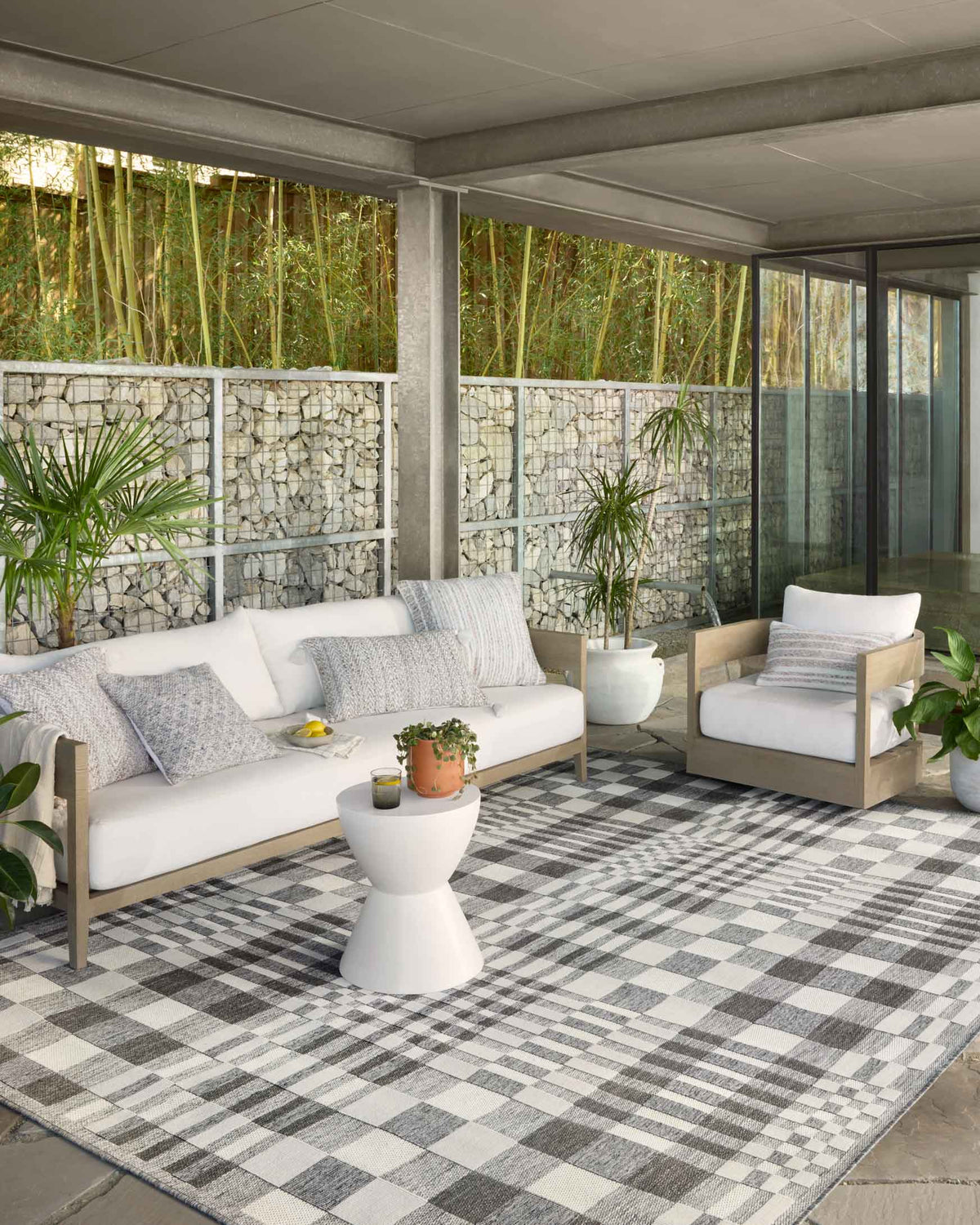 Ivory and pebble checkered indoor/outdoor rug on patio floor, textured flat weave