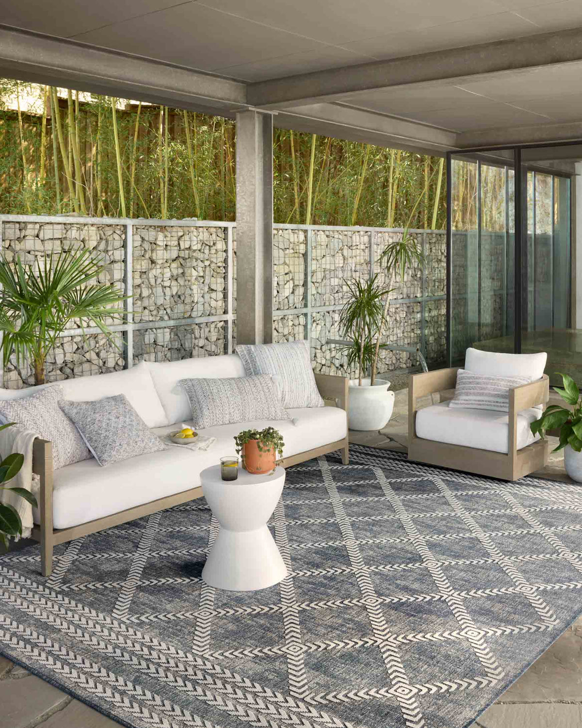 Denim and ivory geometric indoor/outdoor rug laid on a patio.