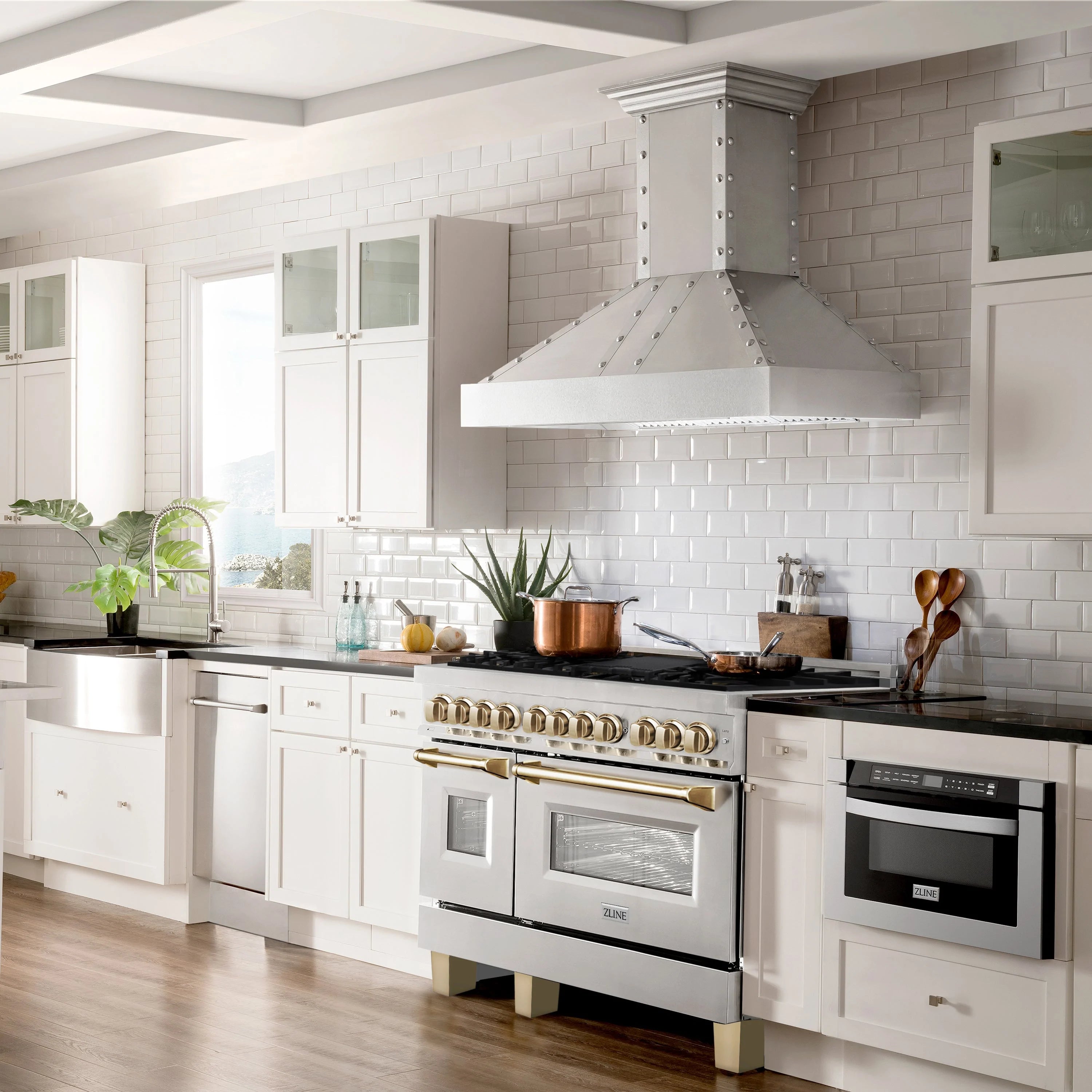 Stainless steel dual fuel range with wall hood and gold trim in kitchen setup