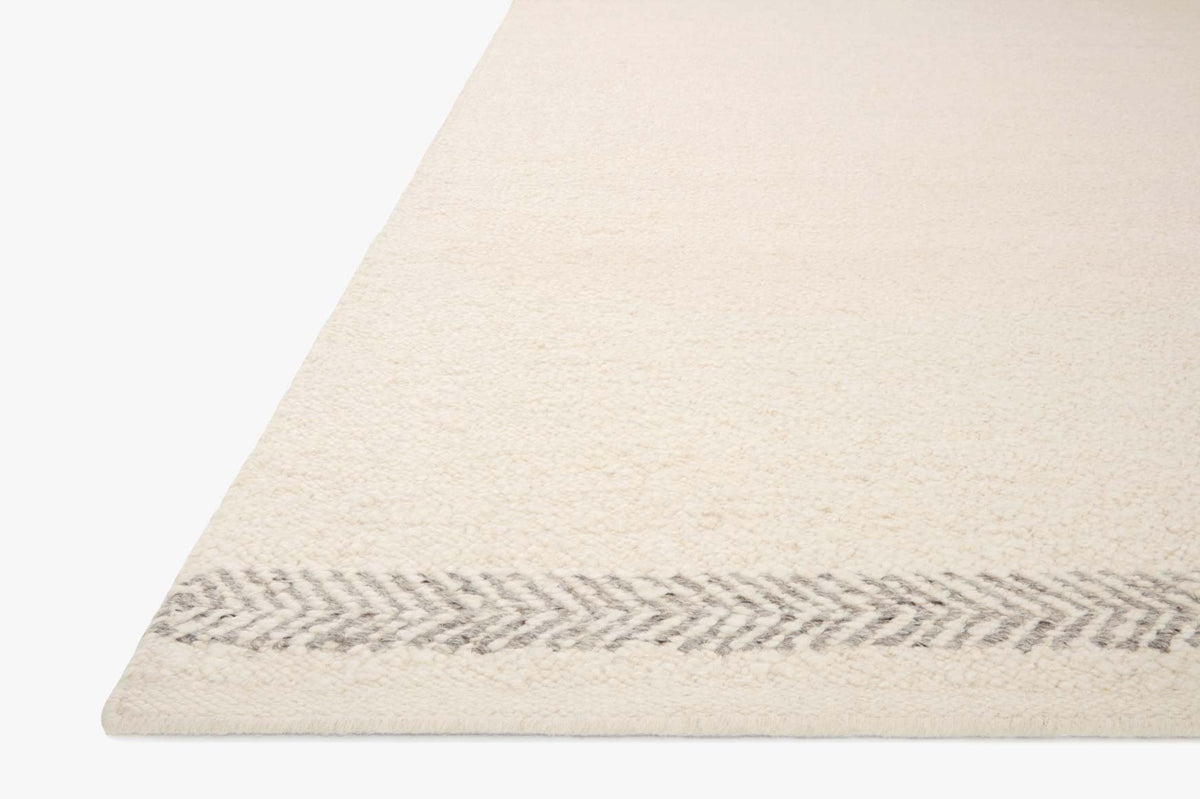 Ivory rug corner with chevron-like silver edge detail