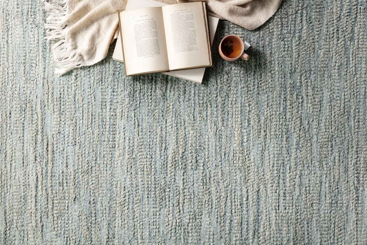 Mist-blue woven rug texture with dense vertical thread lines; close-up detail