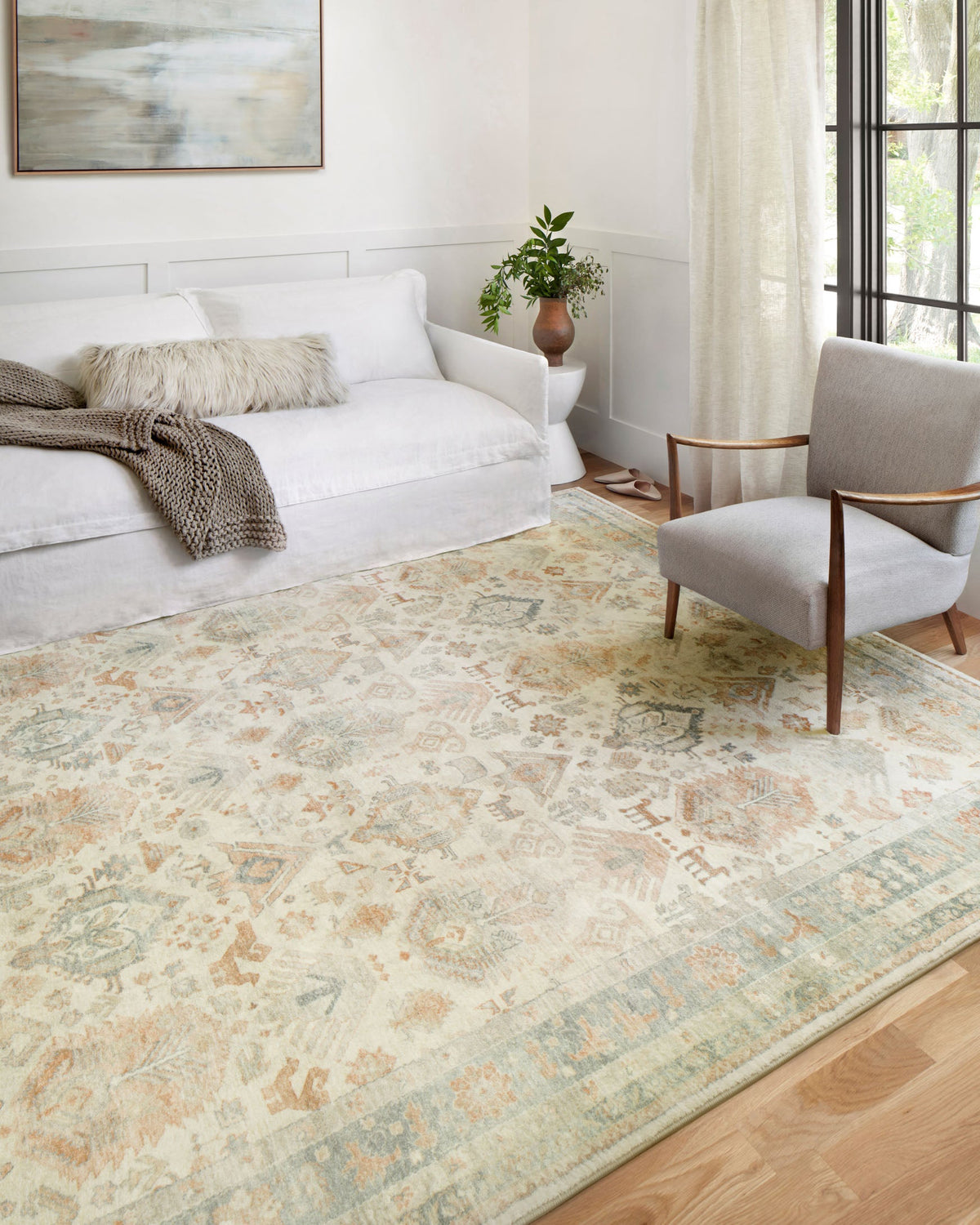 Light beige area rug with faded geometric medallion pattern and subtle border detail