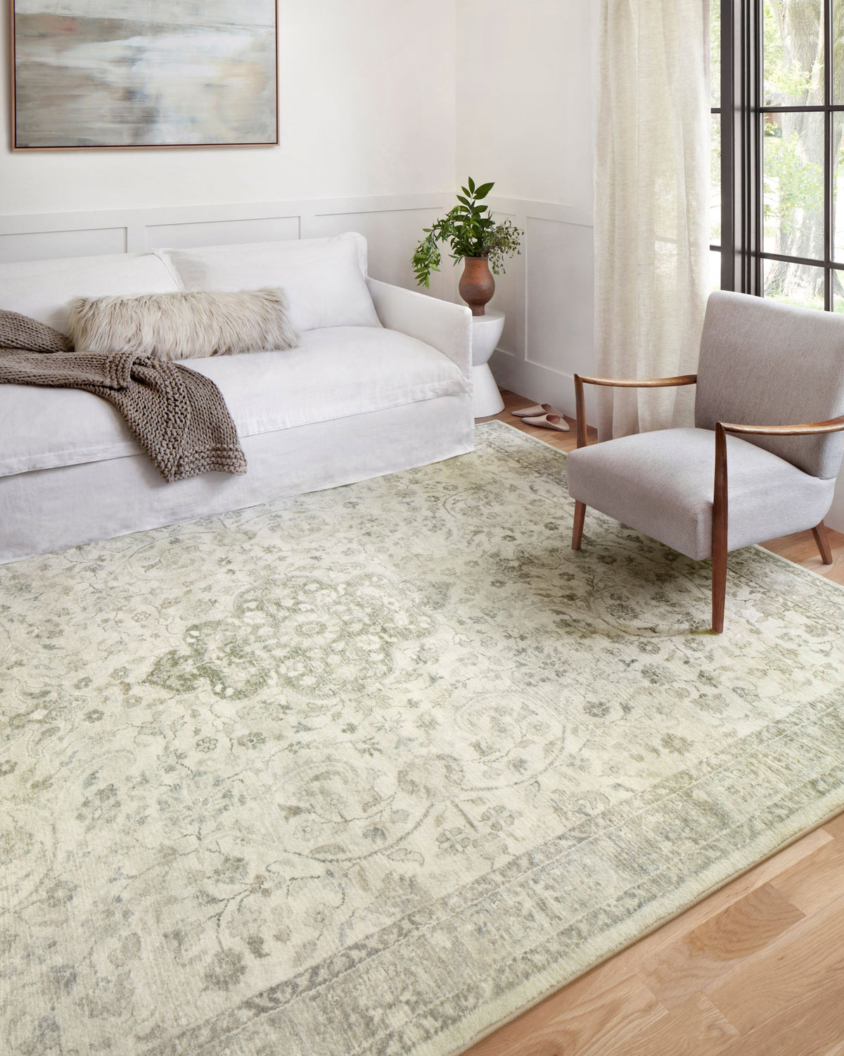 Ivory area rug with faded silver-toned vintage motif pattern in living room