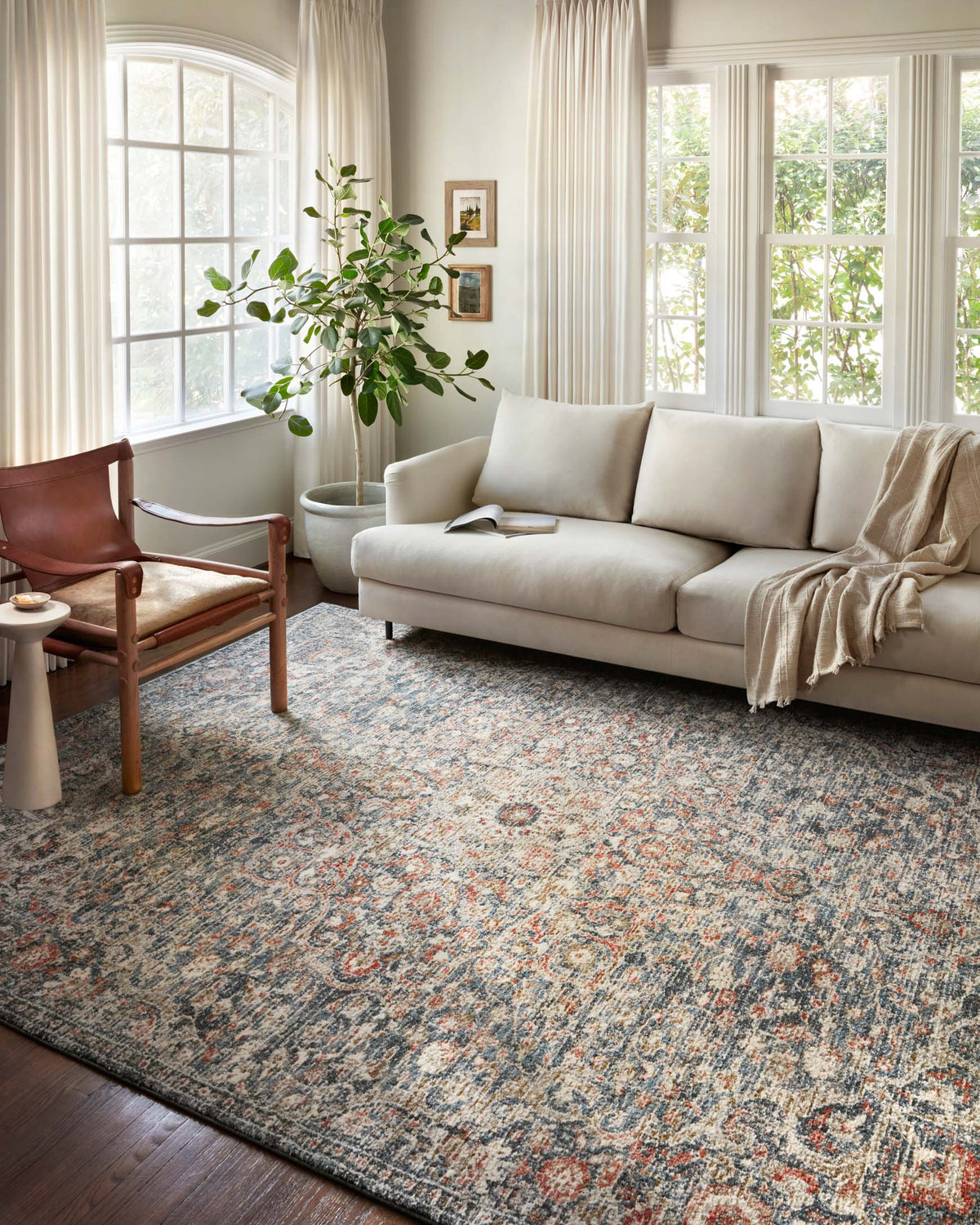 Blue and spice traditional rug with ornate medallion pattern under living room seating.