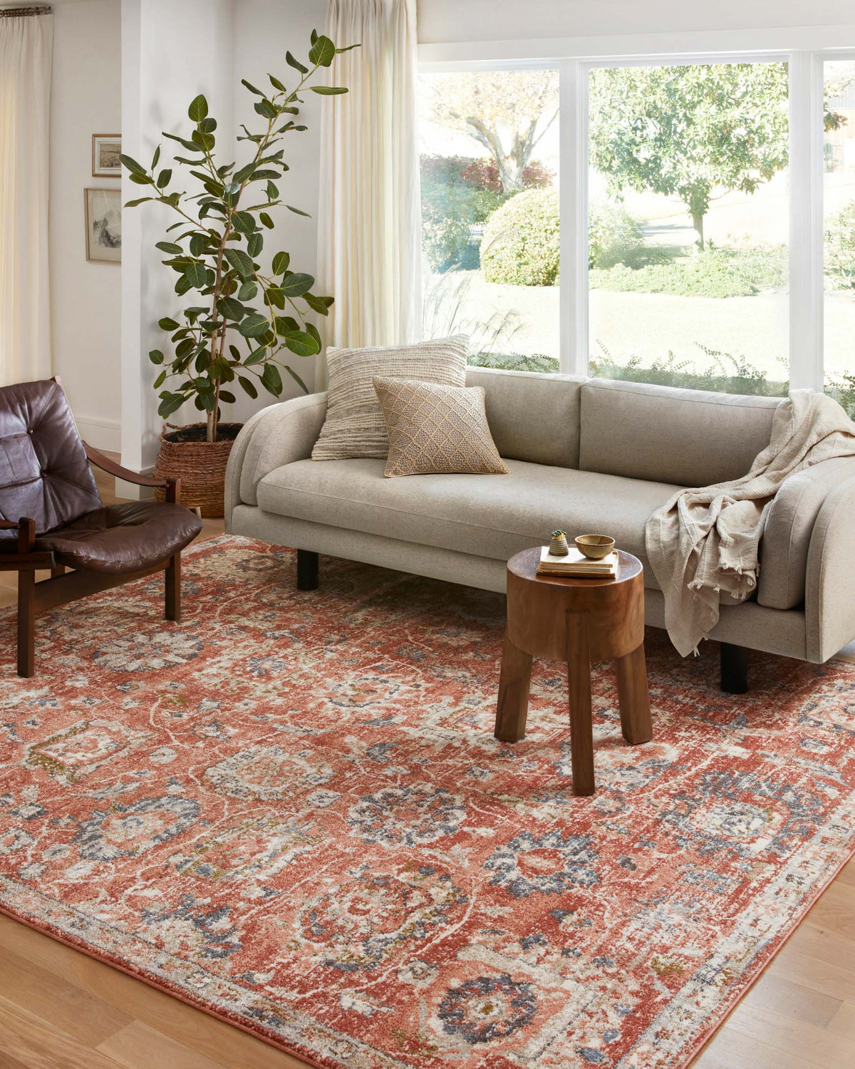 Rust area rug with distressed multi-color medallion and geometric motif.