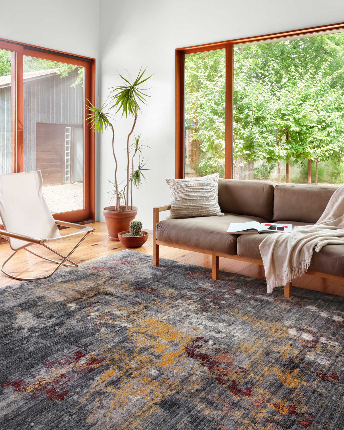 Abstract area rug in dark grey with muted mustard, rust, and beige flecks