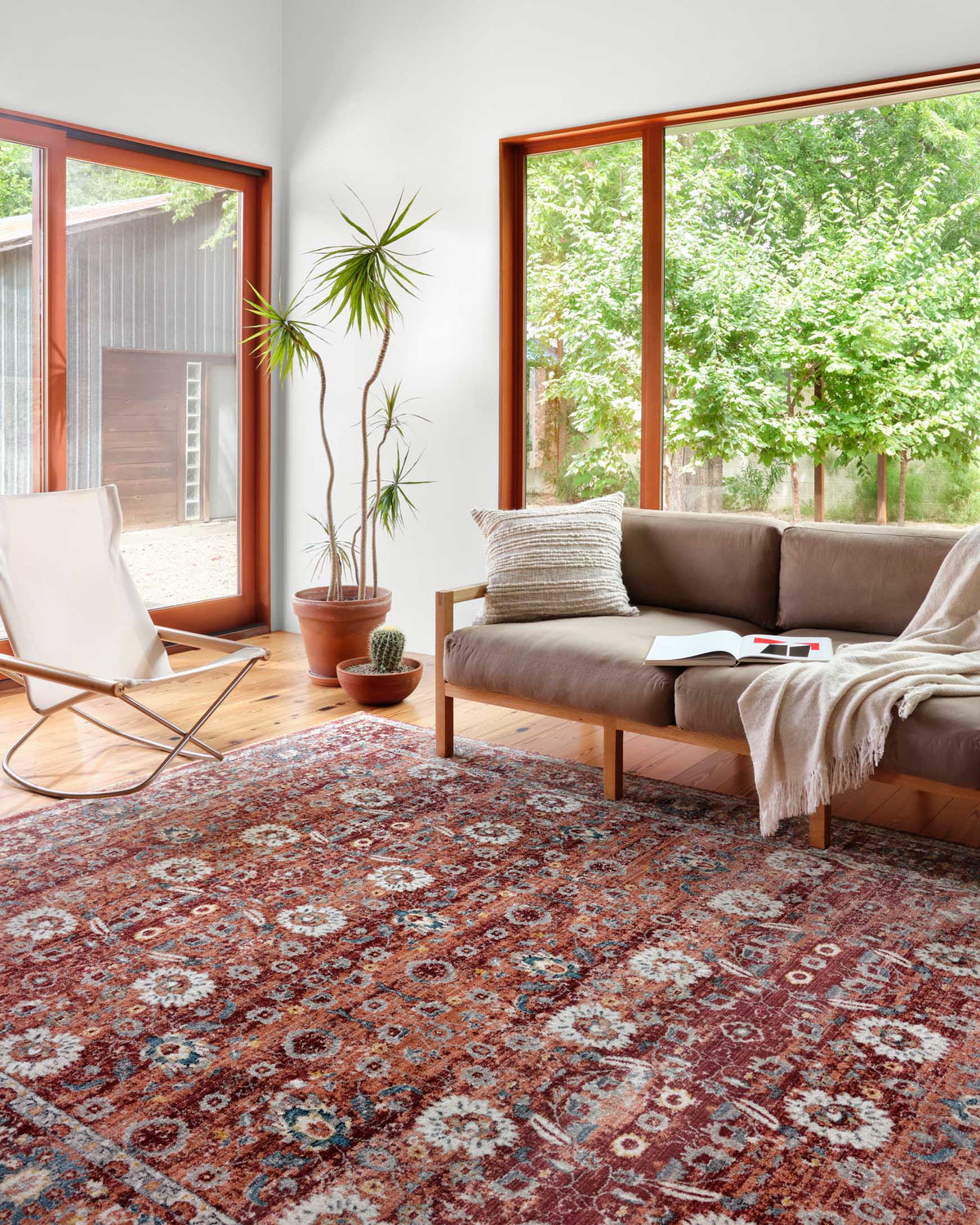 Brick red patterned area rug with blue and cream motifs in a living room setting