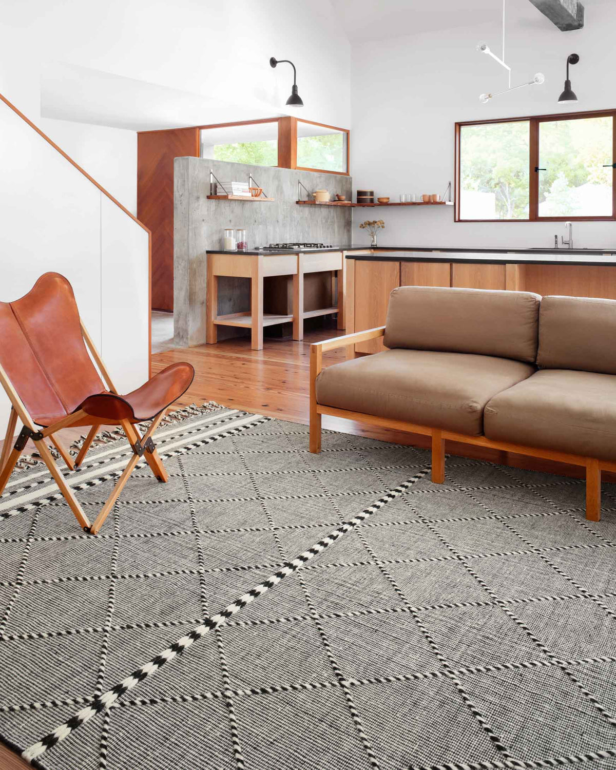 Black-and-gray geometric rug with fringe border, shown on a room floor