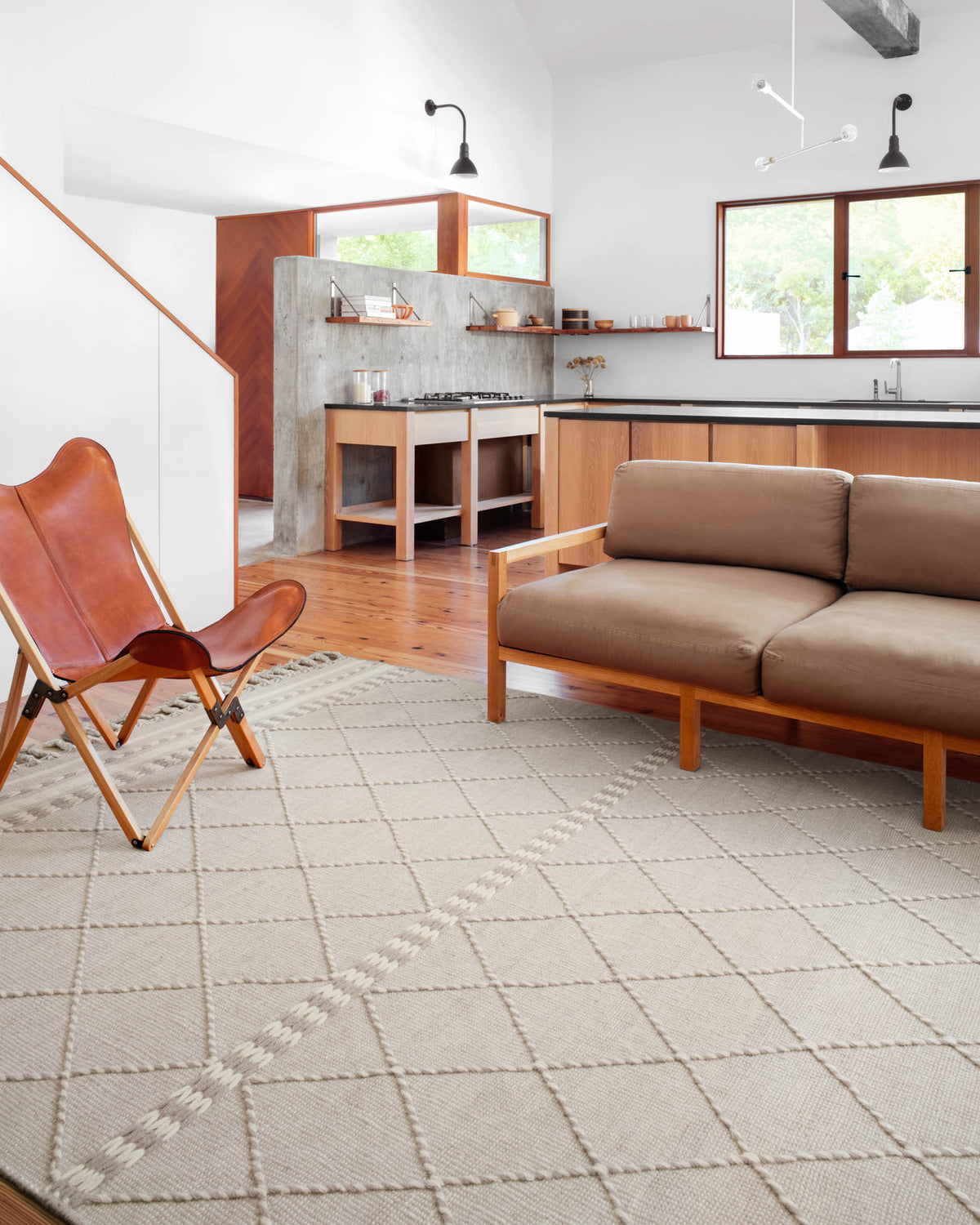 Silver diamond-pattern area rug with fringe tassels laid on the floor