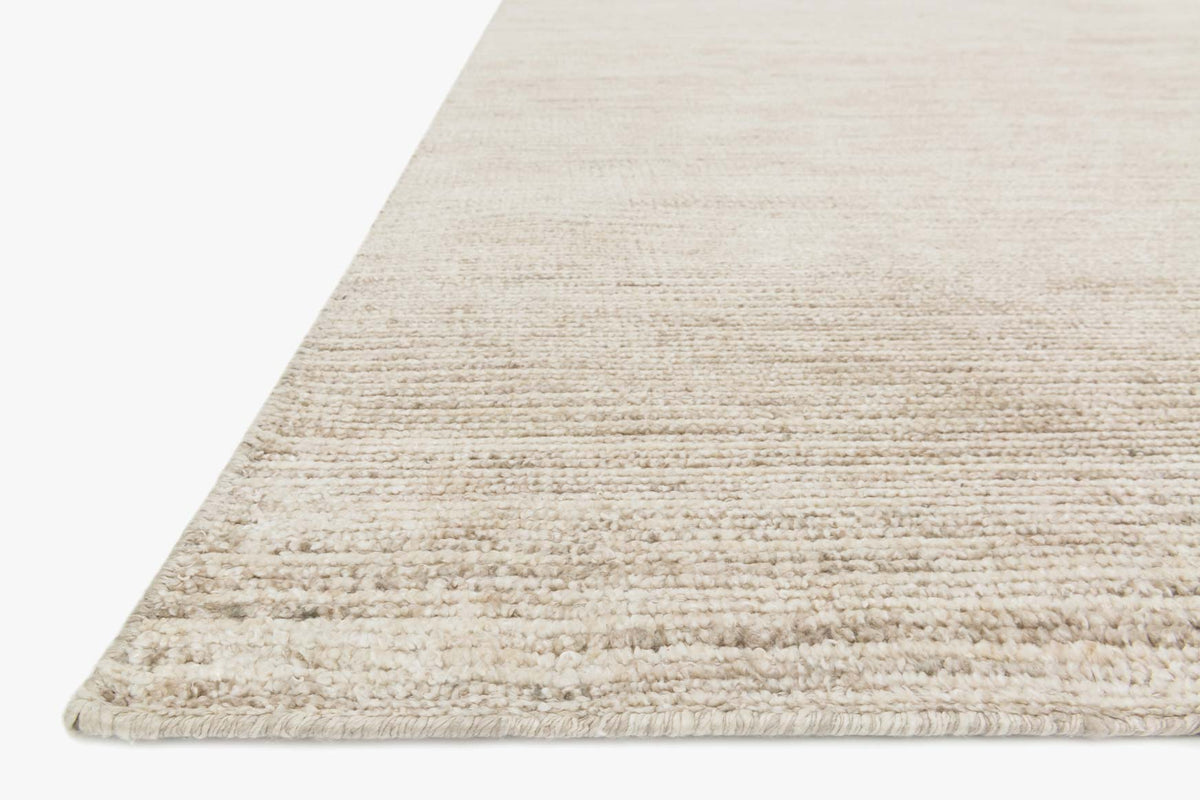 Ivory hand-knotted rug corner with braided edge and layered, low-pile texture