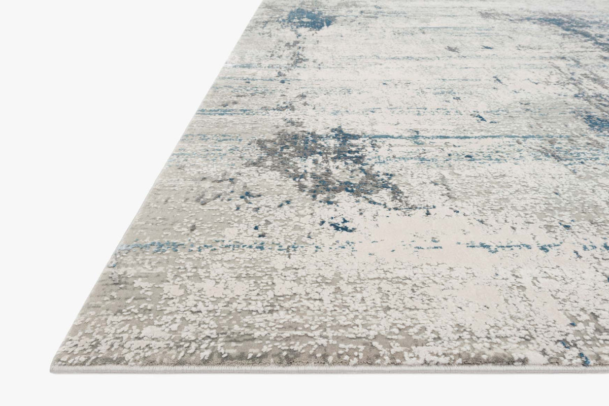 Ivory rug with scattered blue distressed motif and flat woven texture, corner view.