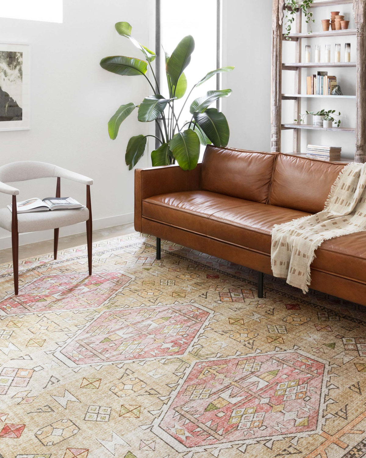Gold and blush geometric area rug laid on floor in a living room setting