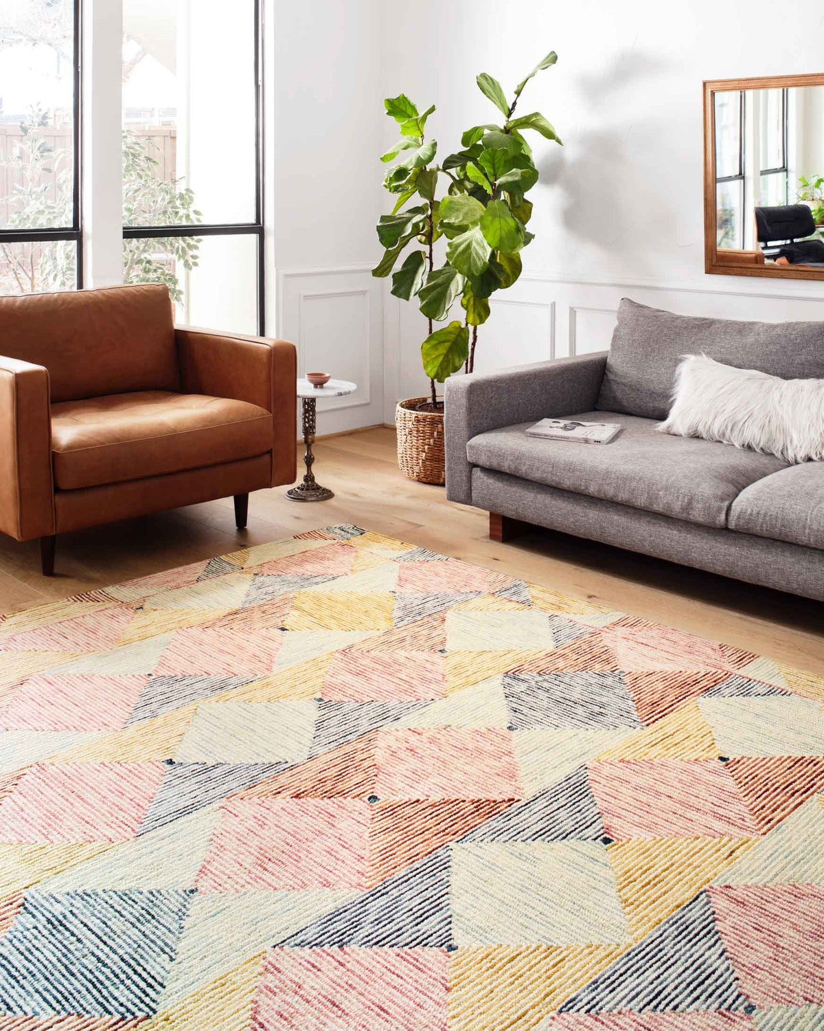 Multicolor geometric hooked rug on floor with diamond shapes in blue, coral, and ivory