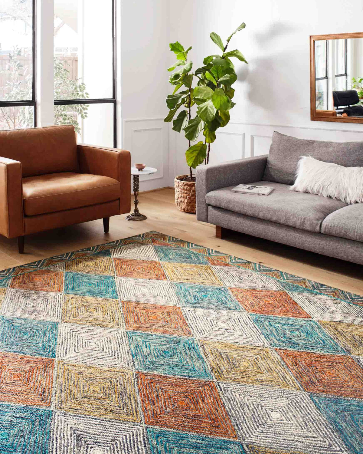 Geometric hooked rug laid in living room, featuring teal, orange, and cream diamond blocks