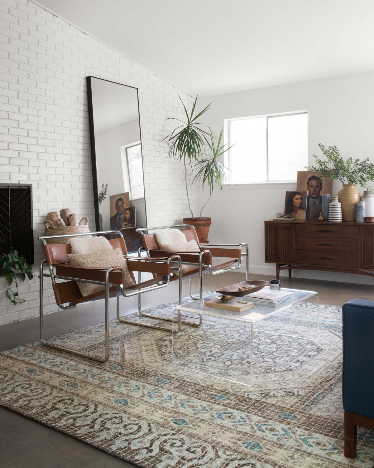 Transitional hooked rug in stone with blue ornamental border, laid in living room